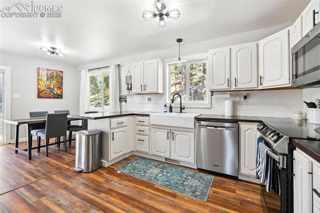 Image 9 of 49: Kitchen with stainless steel appliances, a peninsula, dark countertops, bac