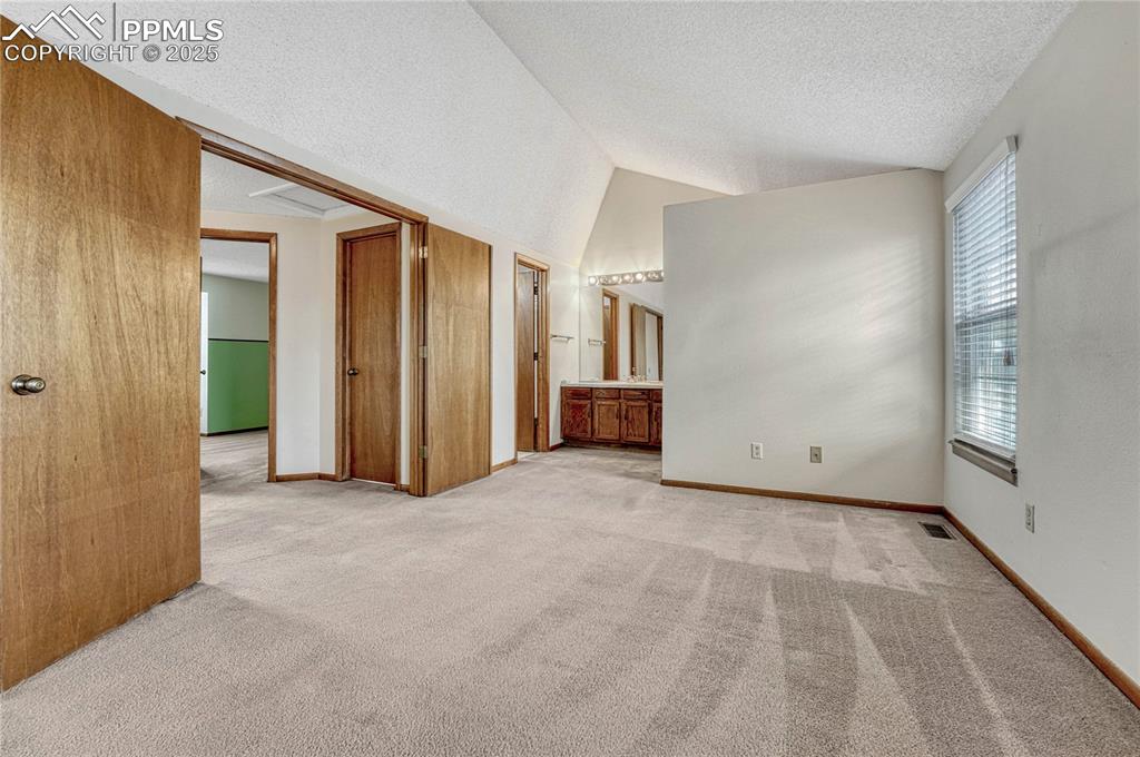 Image 14 of 28: Primary bedroom with vaulted ceiling...