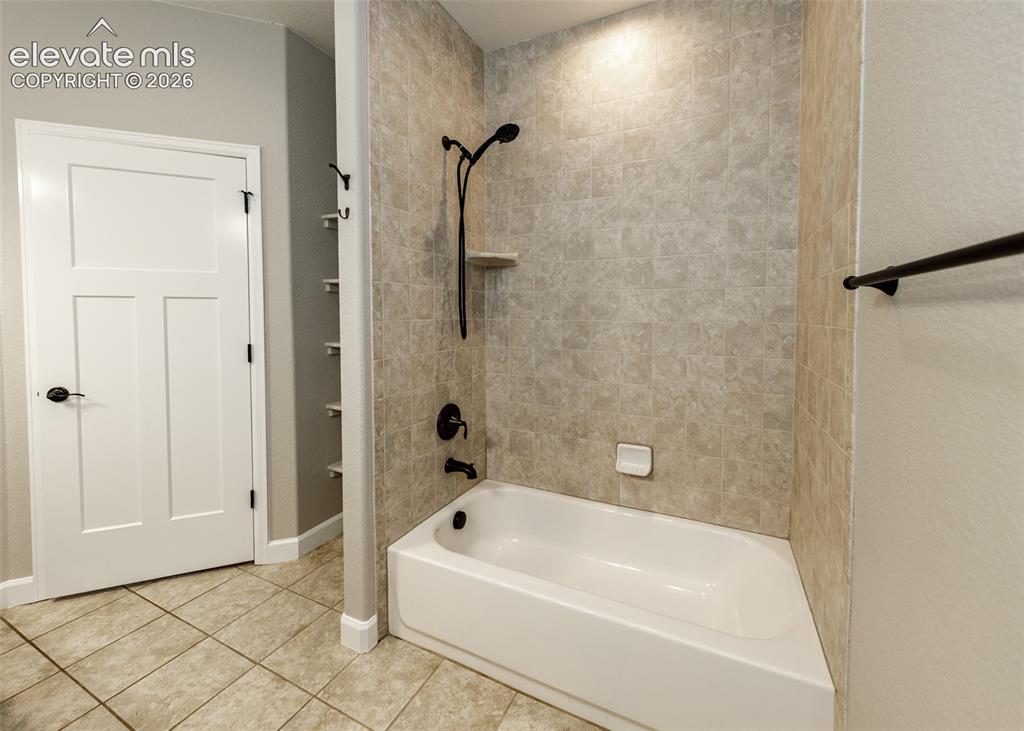 Image 19 of 27: Pretty custom tile in the primary bath. tub/shower.