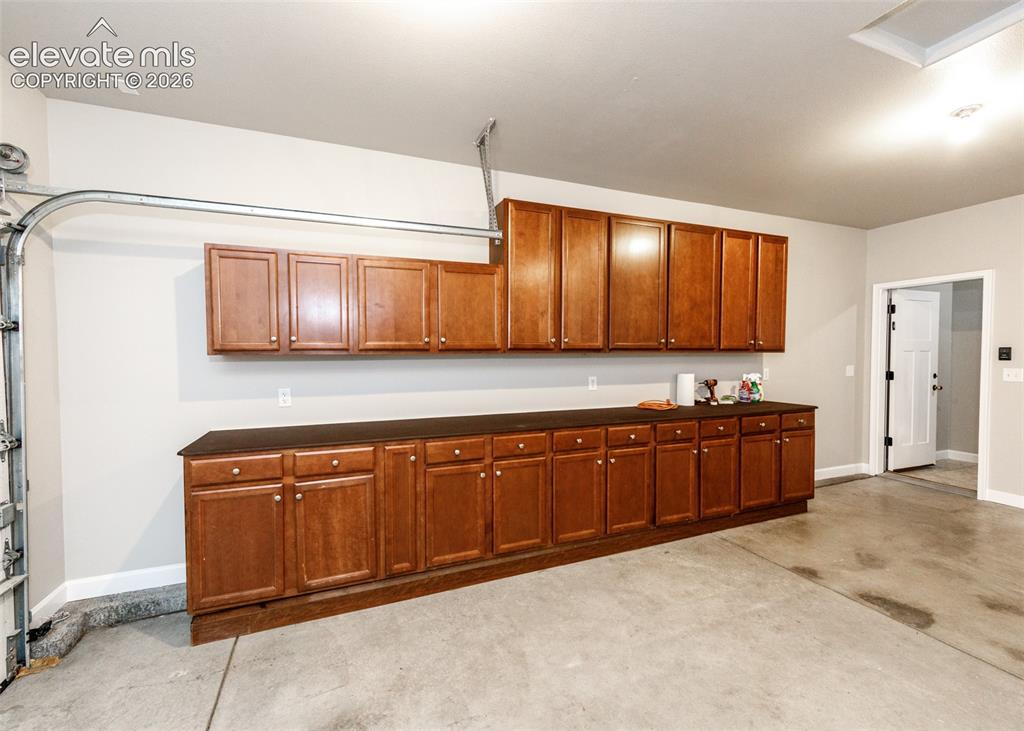Image 23 of 27: Cabinets galore in the attached garage. Uppers and lowers and countertops.