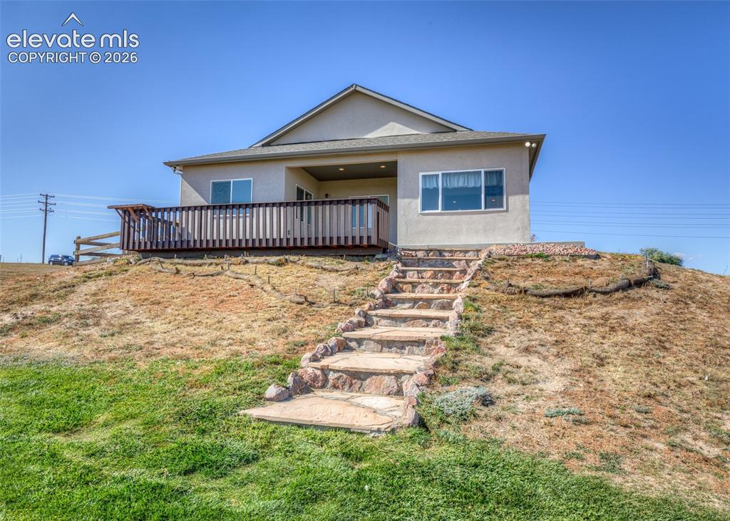 Image 4 of 27: Relax on your deck and enjoy the views! Stone stairs lead to the back grass