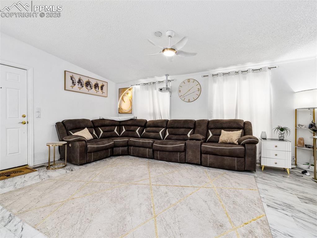 Image 12 of 29: Living room with ceiling fan and a textured ceiling