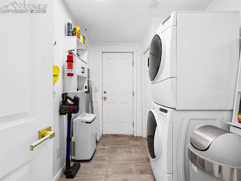Image 17 of 29: Laundry area with light wood-style flooring, stacked washer and dryer, and 