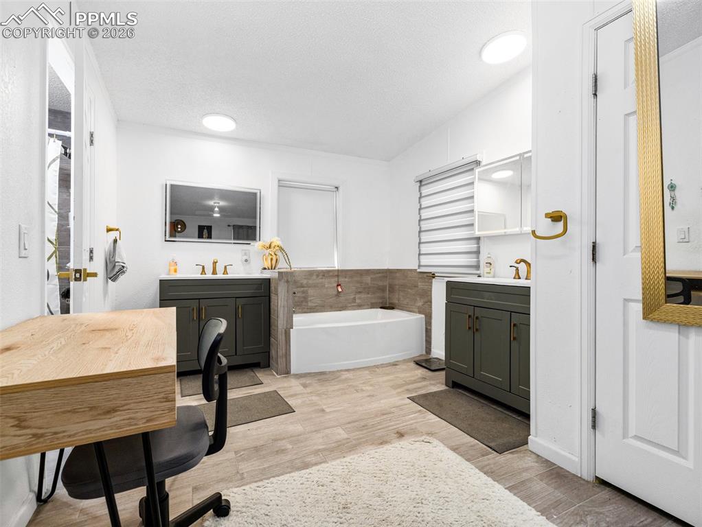 Image 22 of 29: Full bathroom with two vanities, a textured ceiling, light wood-style floor