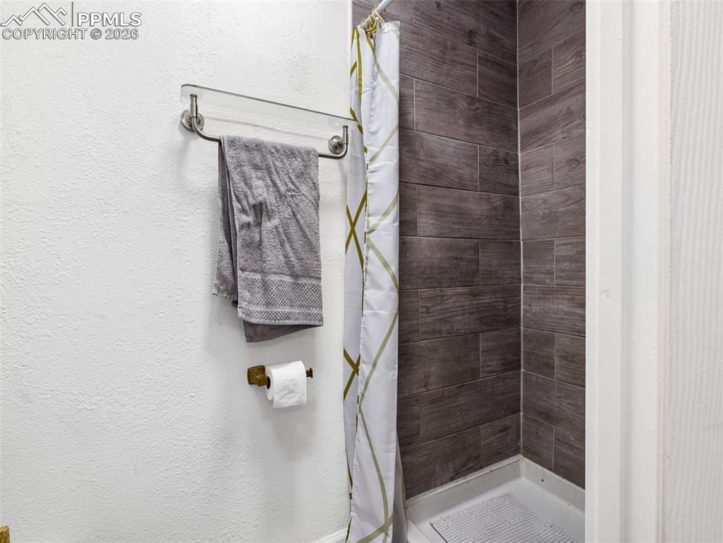 Image 23 of 29: Full bath with a stall shower and a textured wall