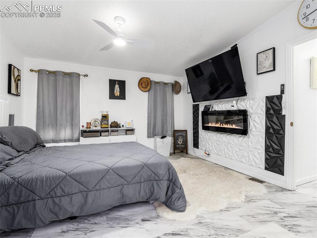 Image 28 of 29: Bedroom with a textured ceiling, marble finish flooring, a ceiling fan, and