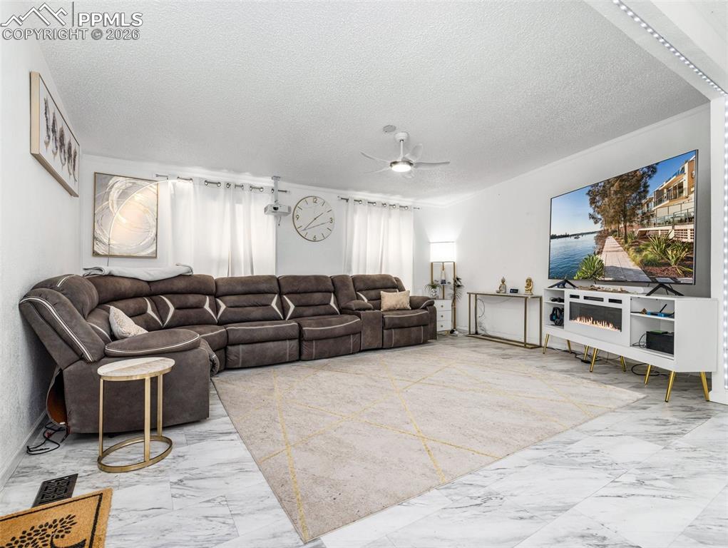 Image 9 of 29: Living area featuring light marble finish floors, a textured ceiling, and a