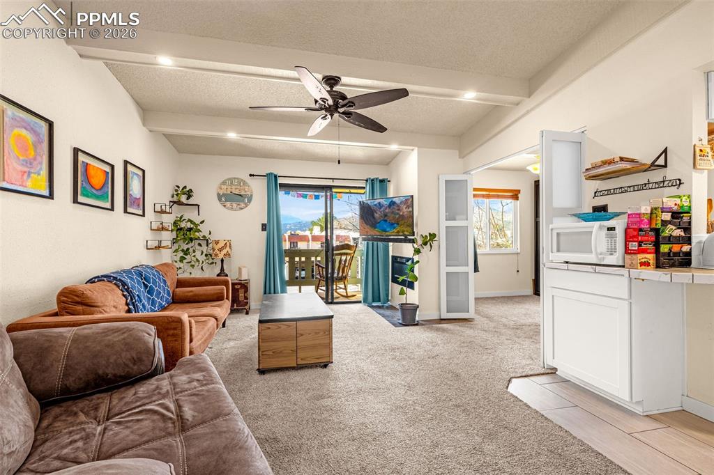 Image 10 of 29: Living area with ceiling fan, a textured ceiling, light colored carpet, bea
