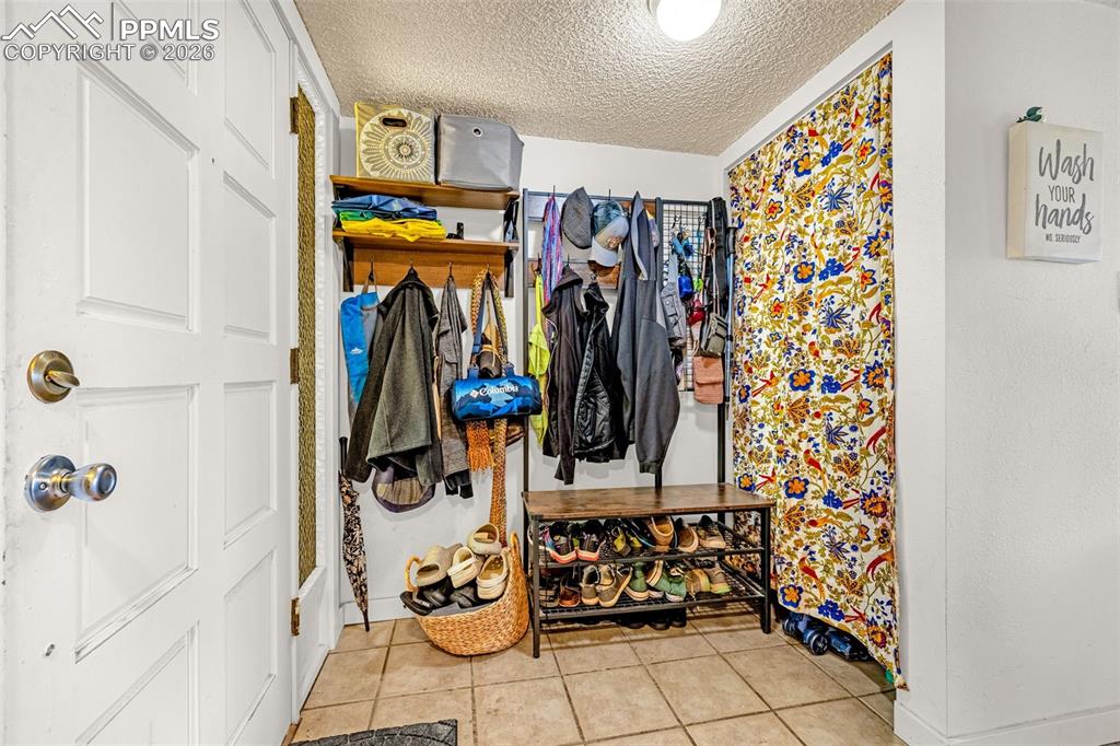 Image 16 of 29: Mudroom featuring a textured ceiling and light tile patterned flooring