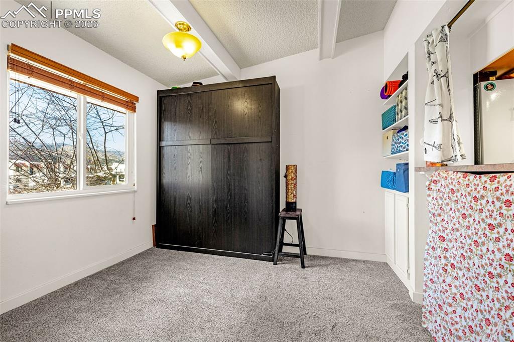 Image 2 of 29: Bedroom with light carpet, a textured ceiling, and beamed ceiling