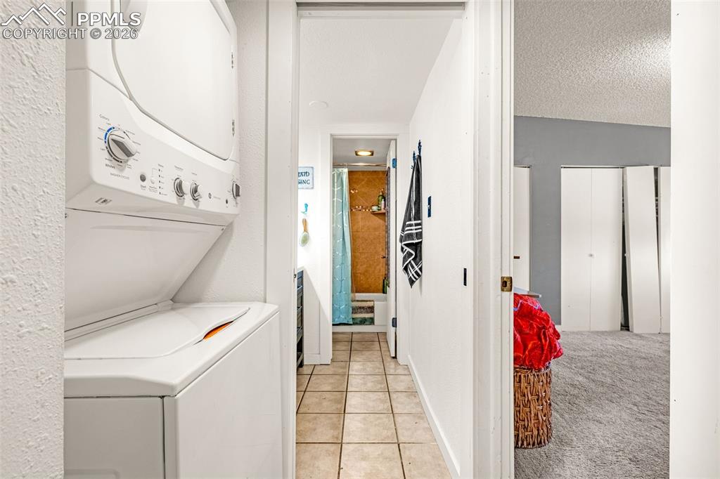 Image 6 of 29: Laundry area featuring light carpet, stacked washer / drying machine, light