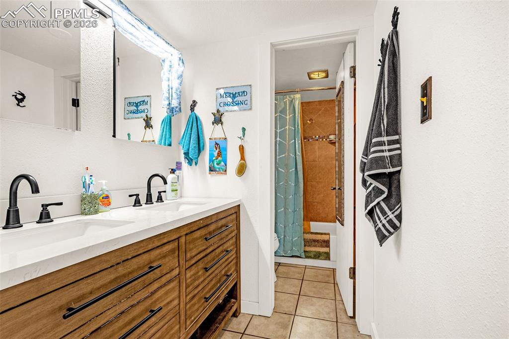 Image 7 of 29: Bathroom with double vanity and light tile patterned flooring