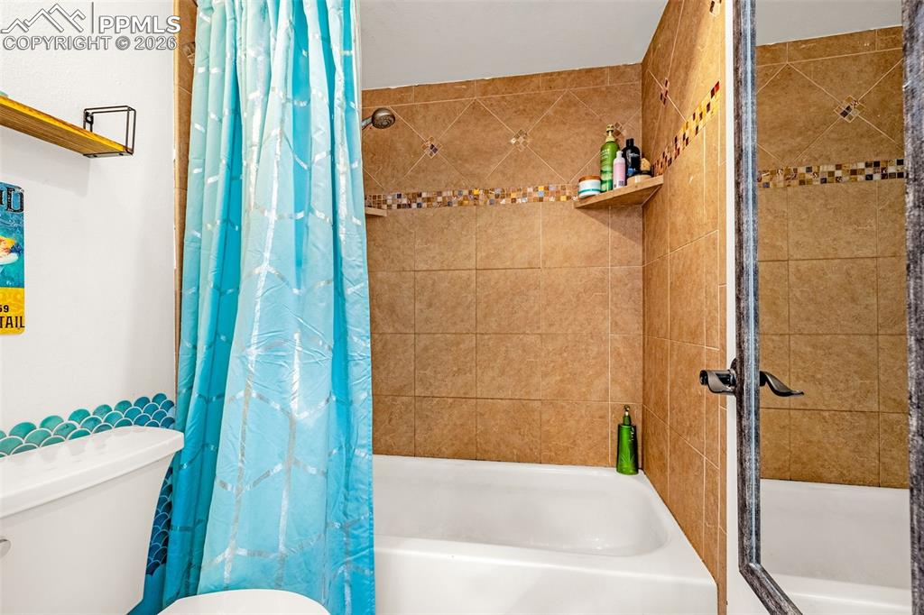 Image 8 of 29: Bathroom featuring shower / bath combination with curtain and toilet