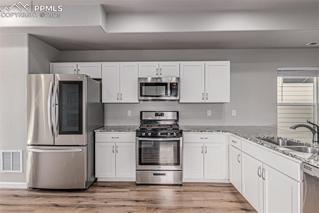 Image 10 of 29: Kitchen featuring appliances with stainless steel finishes, white cabinets,
