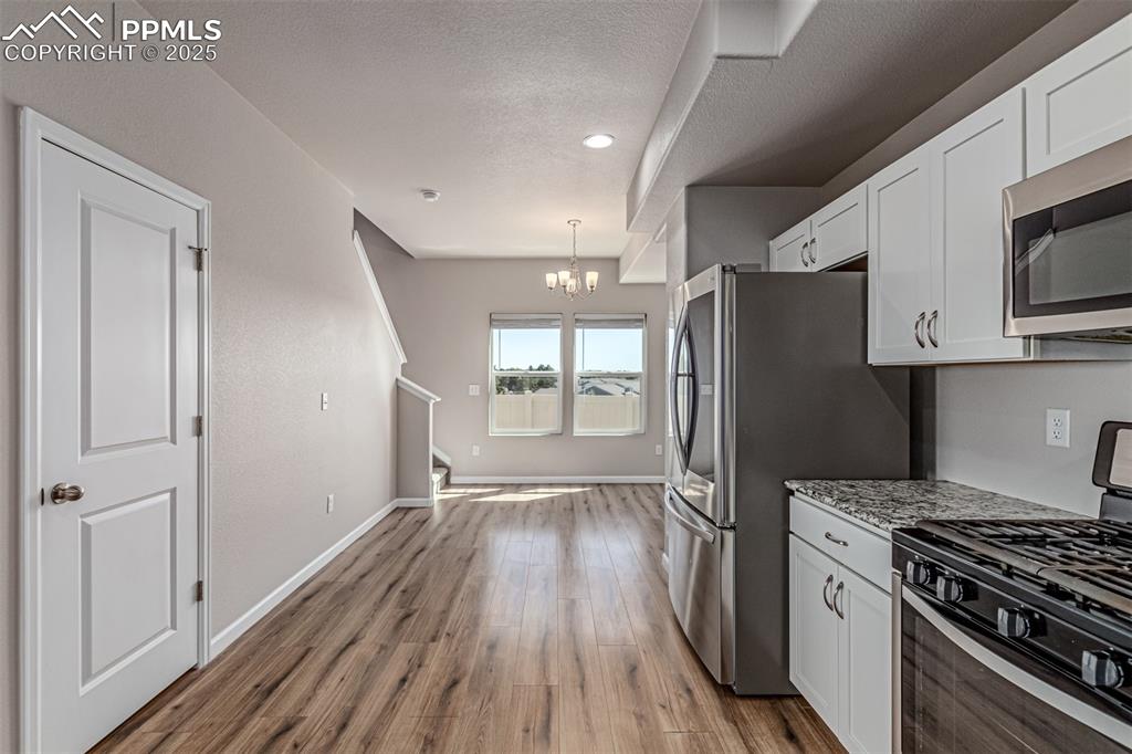 Image 11 of 29: Kitchen featuring appliances with stainless steel finishes, a chandelier, w