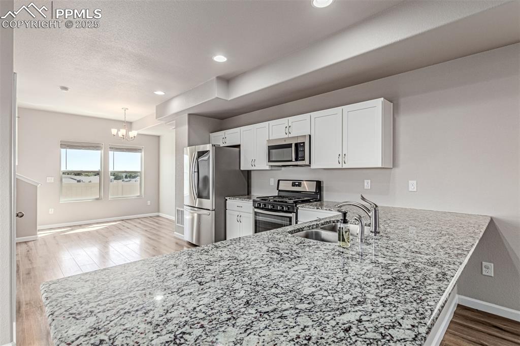Image 9 of 29: Kitchen with stainless steel appliances, a peninsula, light stone counters,