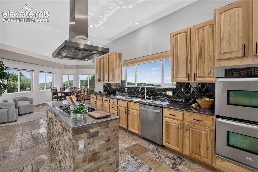 Image 9 of 37: Dual oven & lava onyx travertine flooring that flows into adjacent sunroom