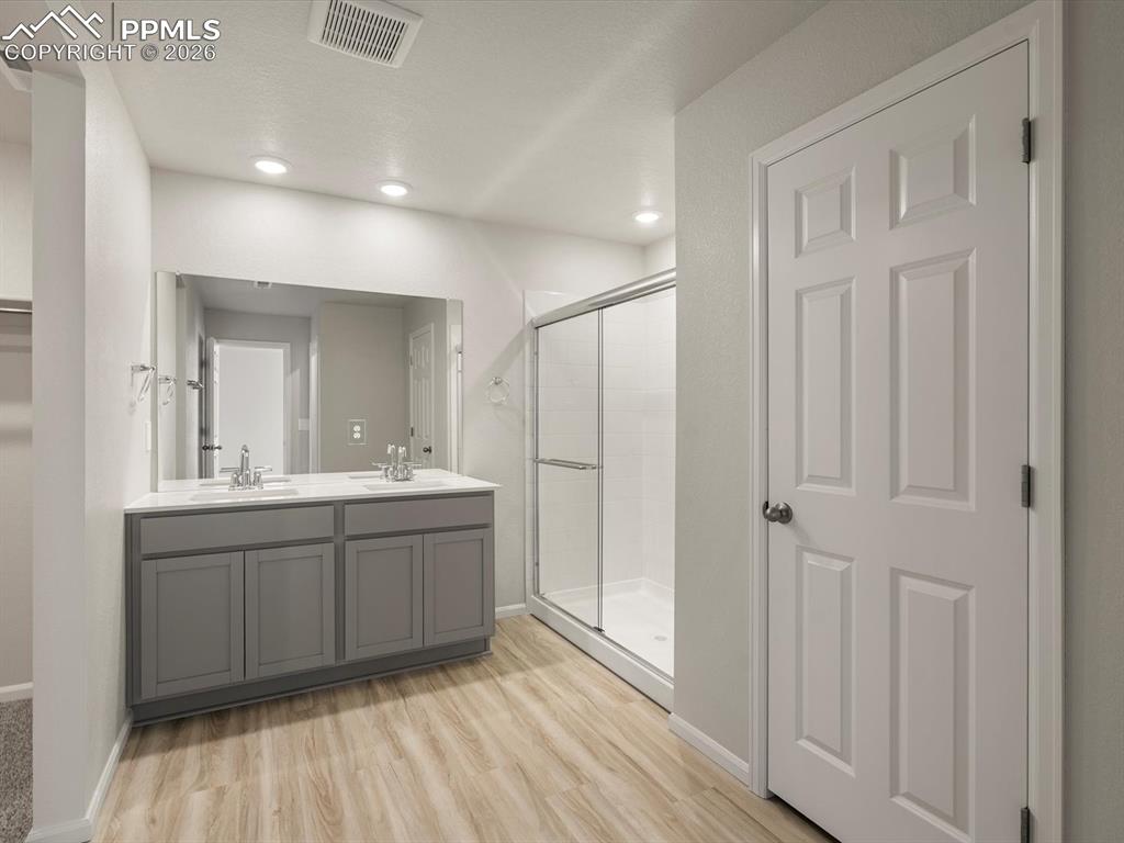 Image 26 of 30: Full bath featuring a shower stall, double vanity, light wood-type flooring