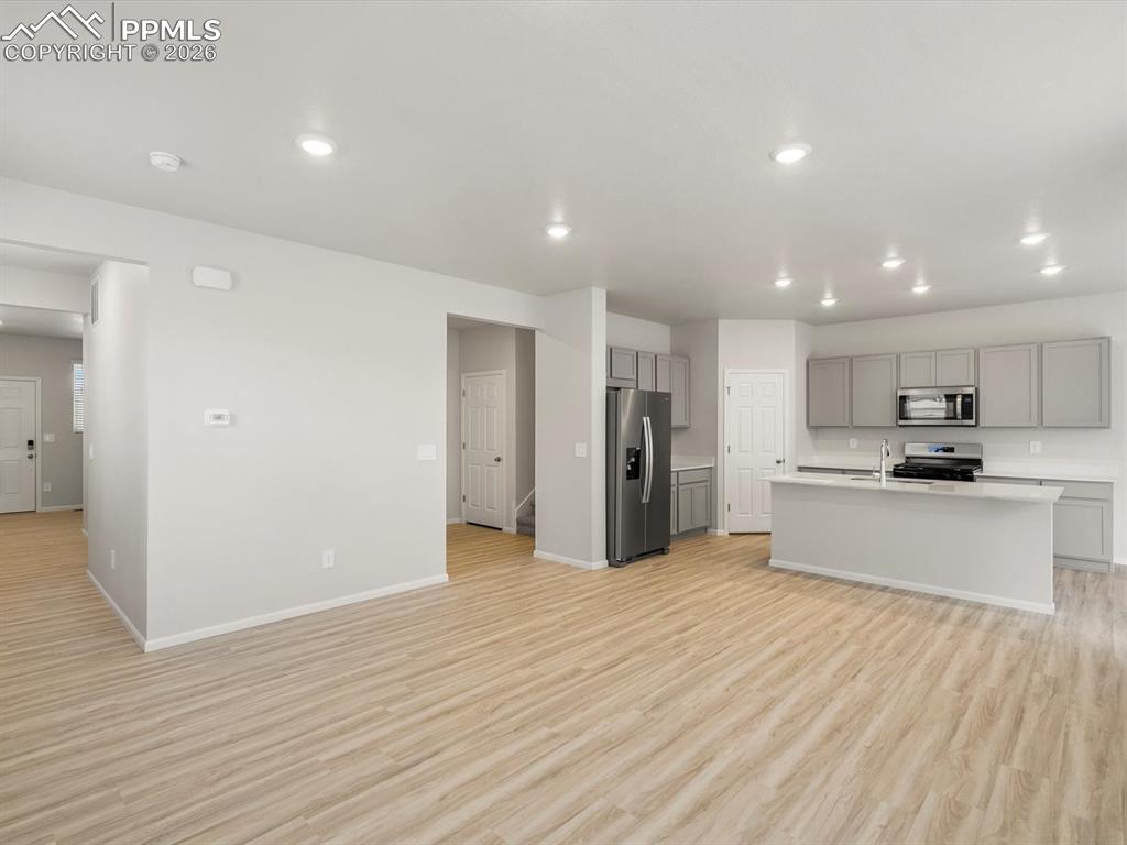 Image 5 of 30: Kitchen with open floor plan, gray cabinetry, light wood finished floors, l