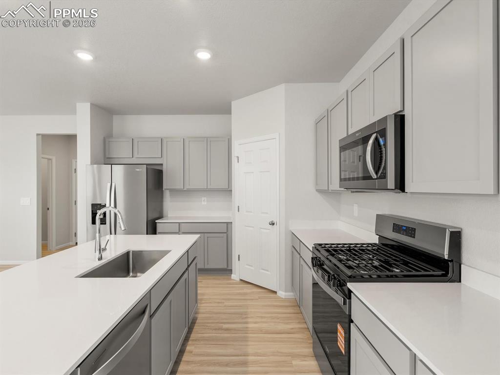Image 7 of 30: Kitchen featuring appliances with stainless steel finishes, light wood-styl