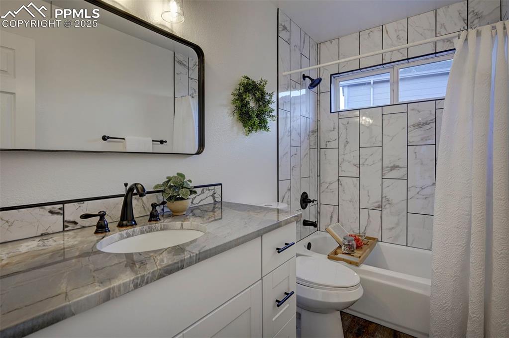 Image 27 of 50: Remodeled Main Level Bathroom with vanity, quartz countertop, framed mirror
