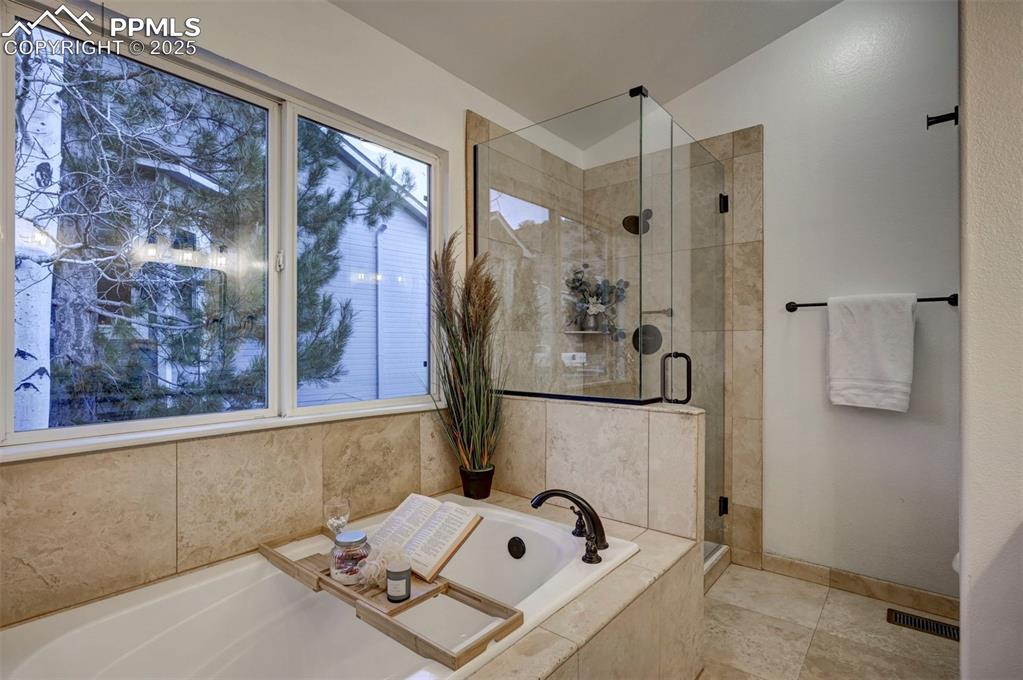 Image 32 of 50: Tiled soaking tub and shower in the Primary Bathroom. New glass around encl