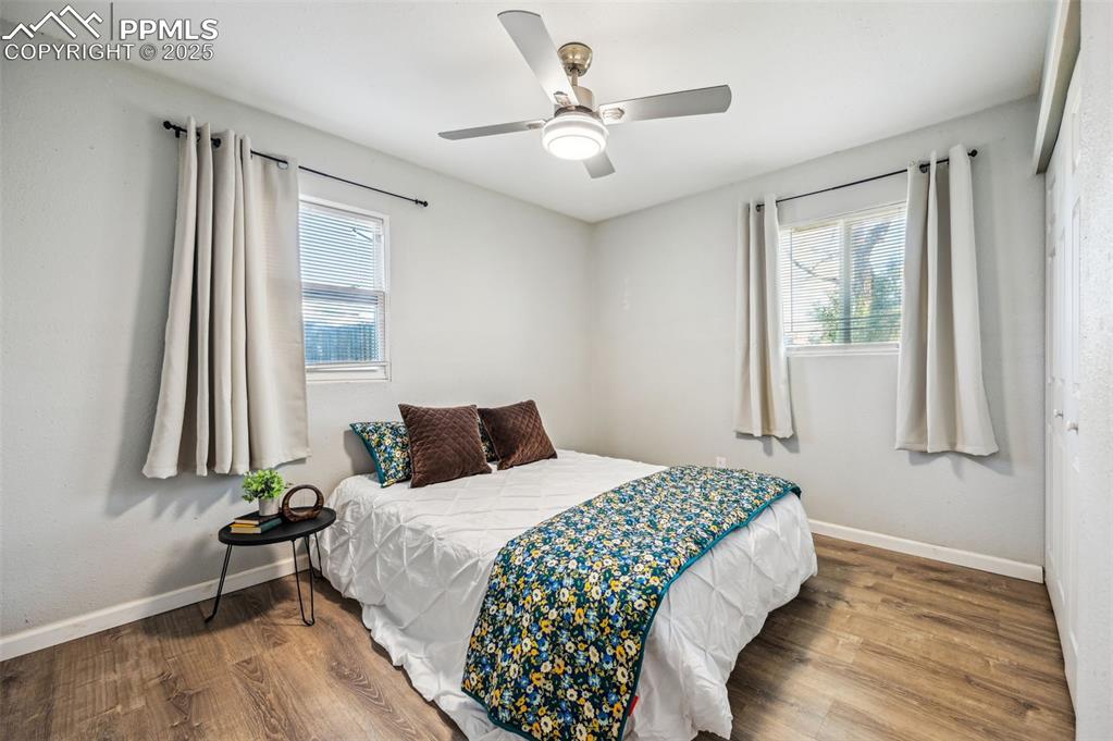 Image 15 of 27: Bedroom with wood finished floors, a ceiling fan, and multiple windows