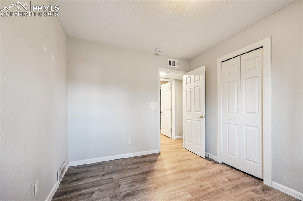 Image 23 of 27: Unfurnished bedroom featuring light wood finished floors, a textured ceilin