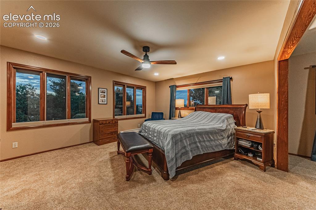 Image 18 of 43: Carpeted bedroom with ceiling fan and multiple windows