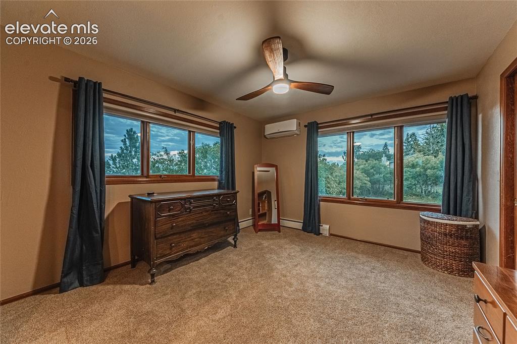 Image 20 of 43: Misc room with a wall unit AC, ceiling fan, and light colored carpet