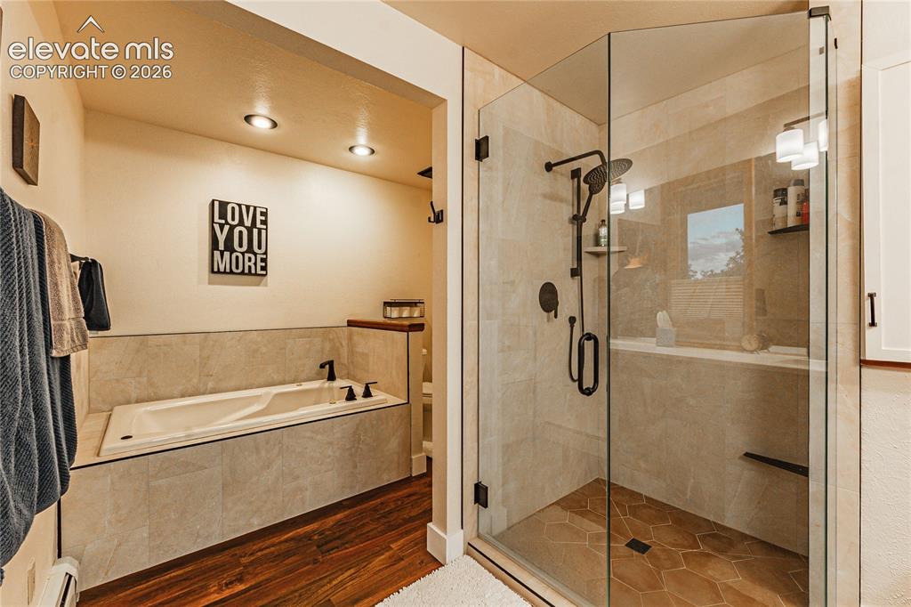Image 23 of 43: Bathroom with a baseboard radiator, plus walk in shower, and hardwood / woo