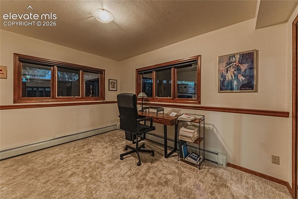 Image 28 of 43: Carpeted office space with a textured ceiling and a baseboard radiator