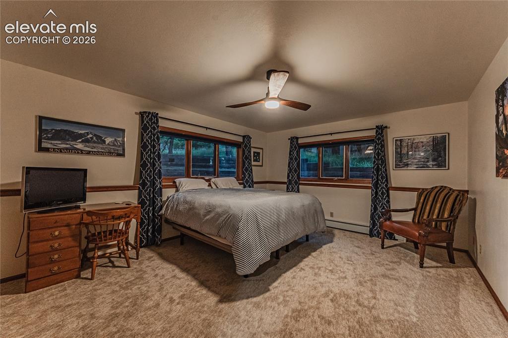 Image 31 of 43: Bedroom with ceiling fan, light colored carpet, and a baseboard radiator