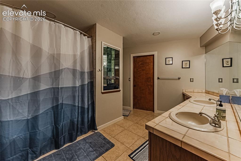 Image 33 of 43: Bathroom featuring walk in shower, vanity, tile patterned flooring, and a t