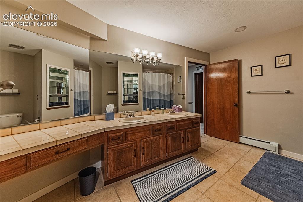 Image 34 of 43: Bathroom featuring tile patterned flooring, a textured ceiling, a baseboard