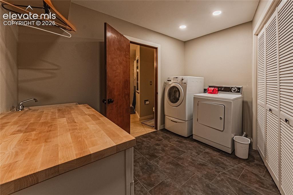 Image 35 of 43: Laundry area with washer and clothes dryer and dark tile patterned flooring