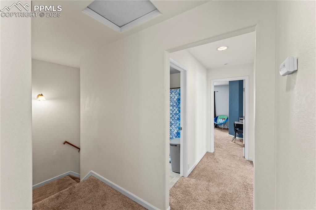 Image 14 of 25: Hallway with light carpet and an upstairs landing