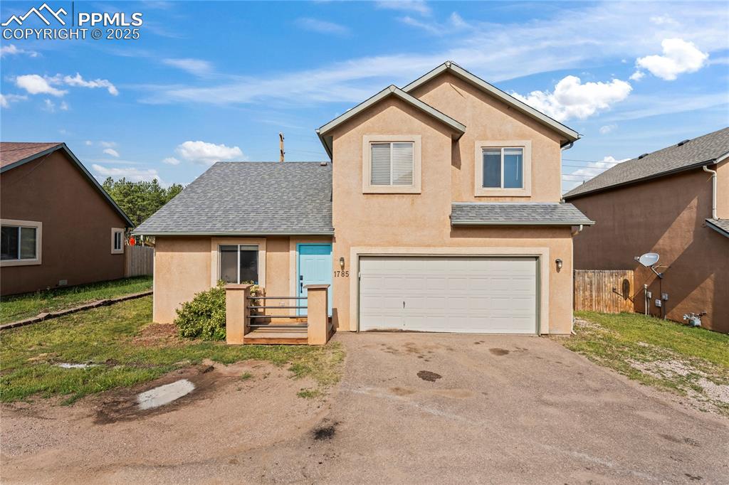 Caption: Traditional-style house with a shingled roof, asphalt driveway, stucco siding, and an attached garag