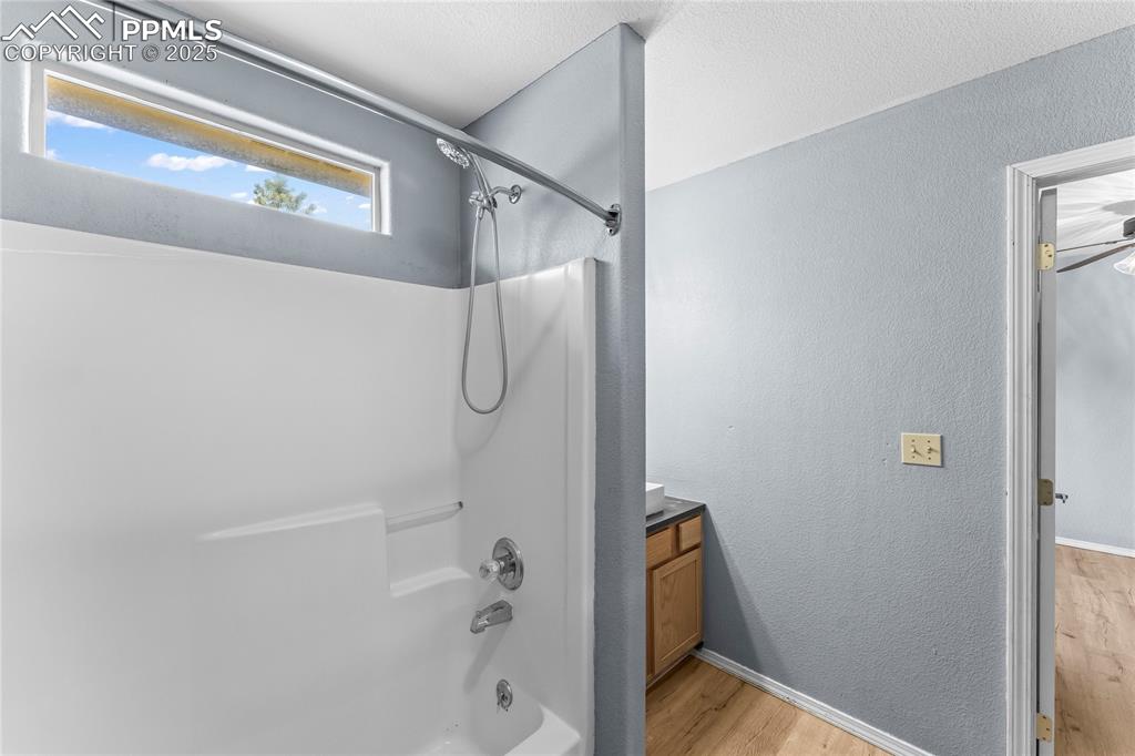 Image 18 of 37: Full bath with shower / washtub combination, wood finished floors, a textur