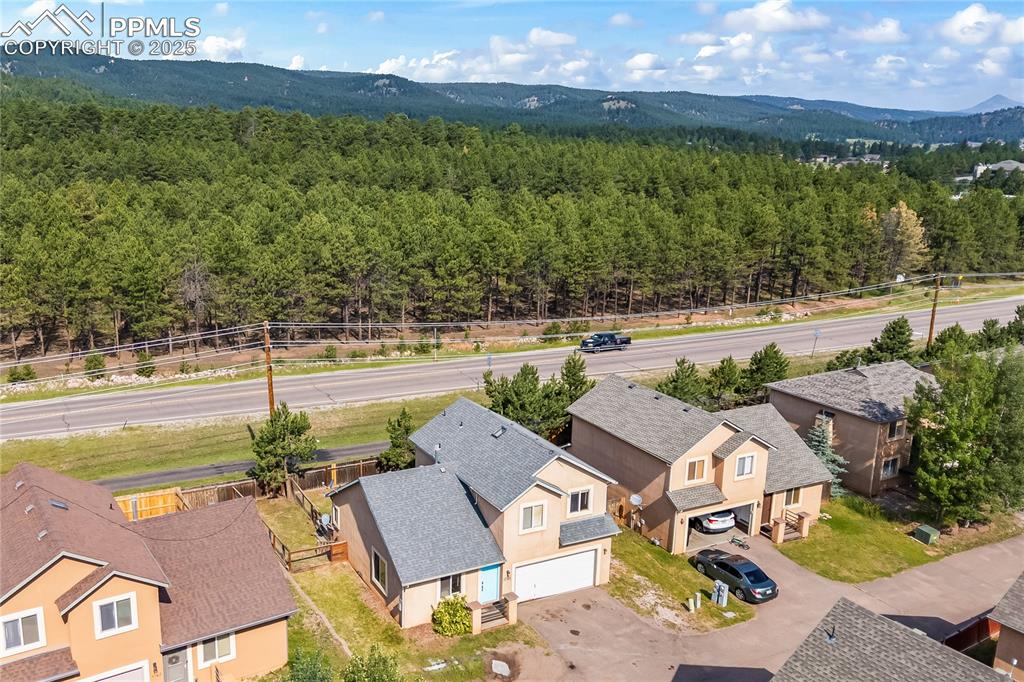 Image 29 of 37: Aerial view of residential area with a forest and mountains