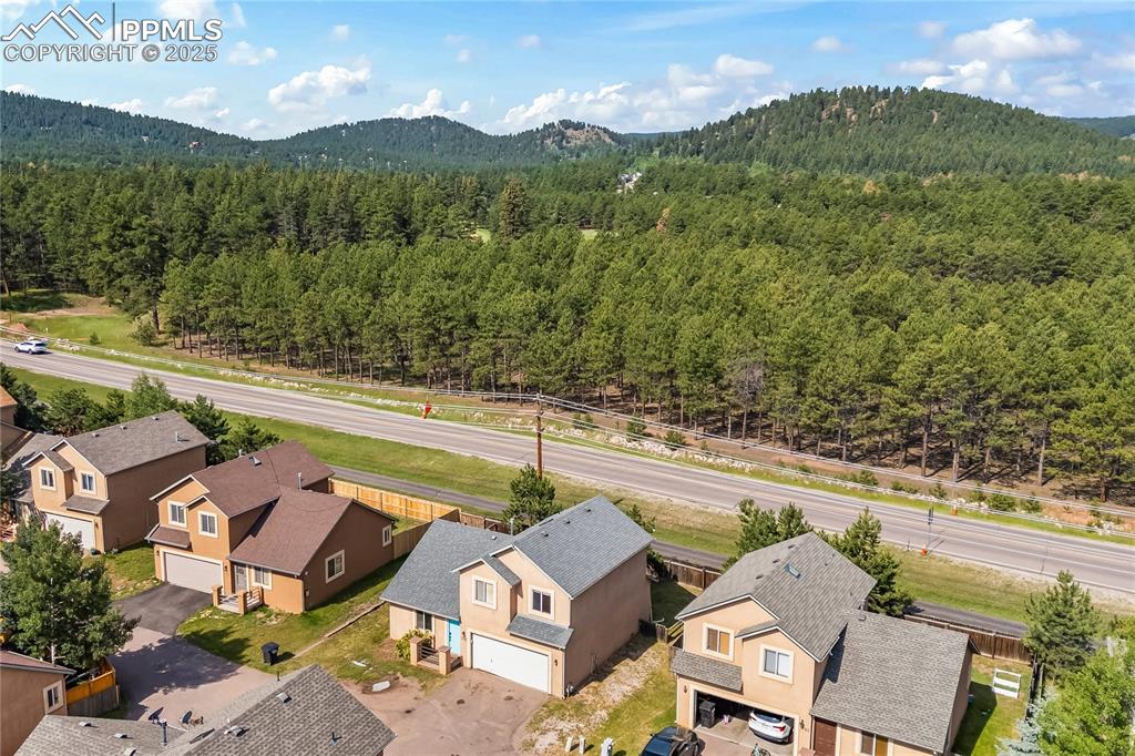 Image 31 of 37: Aerial perspective of suburban area featuring a forest and a mountainous ba