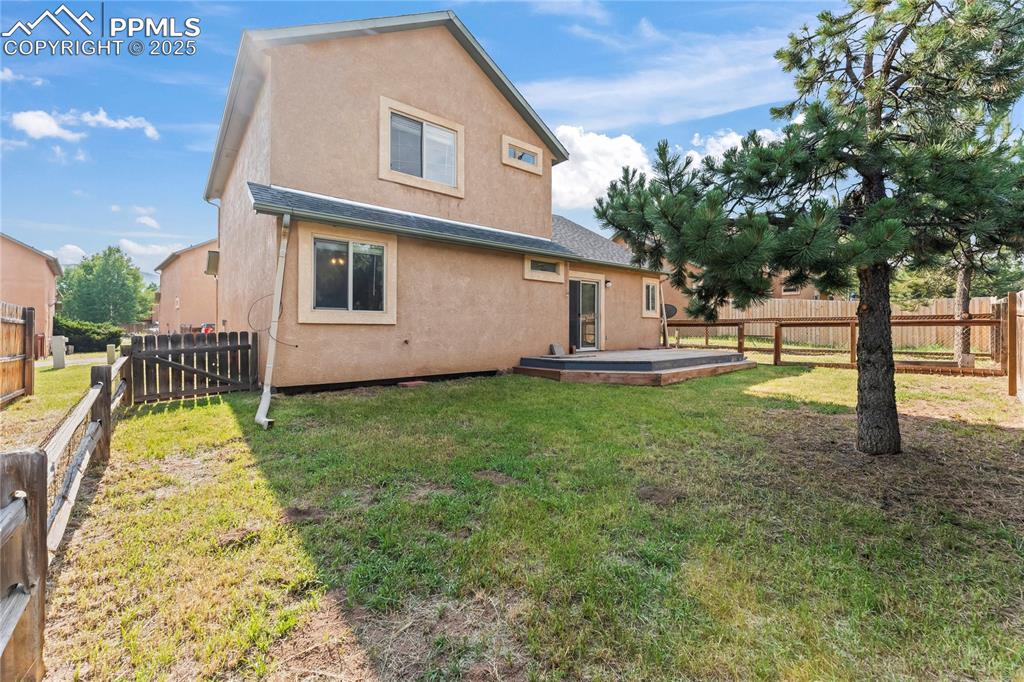 Image 4 of 37: Rear view of house with stucco siding, a fenced backyard, and a deck