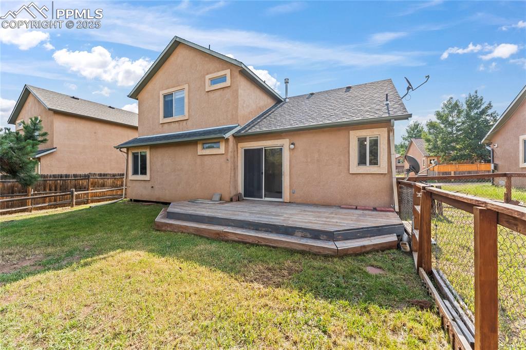 Image 5 of 37: Rear view of property featuring a fenced backyard, a wooden deck, and stucc