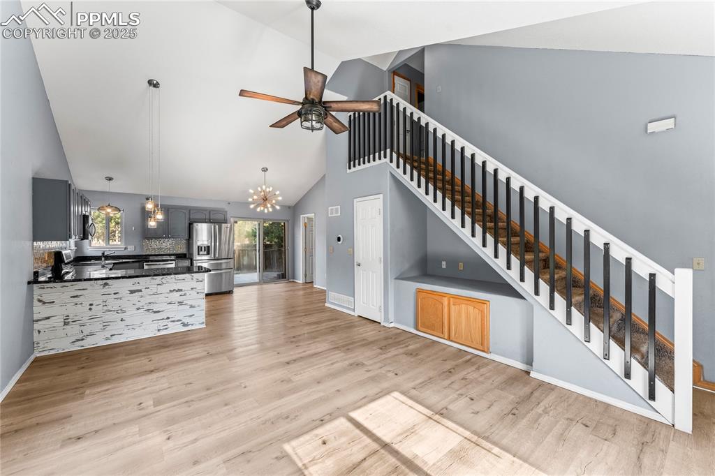 Image 9 of 37: Unfurnished living room with stairway, a chandelier, high vaulted ceiling,