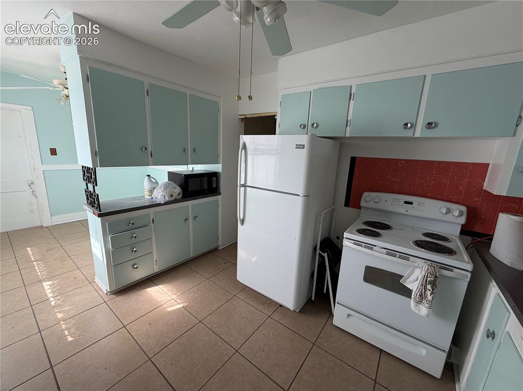 Image 2 of 28: Tiled flooring with light-colored grout, light blue cabinetry with silver-t