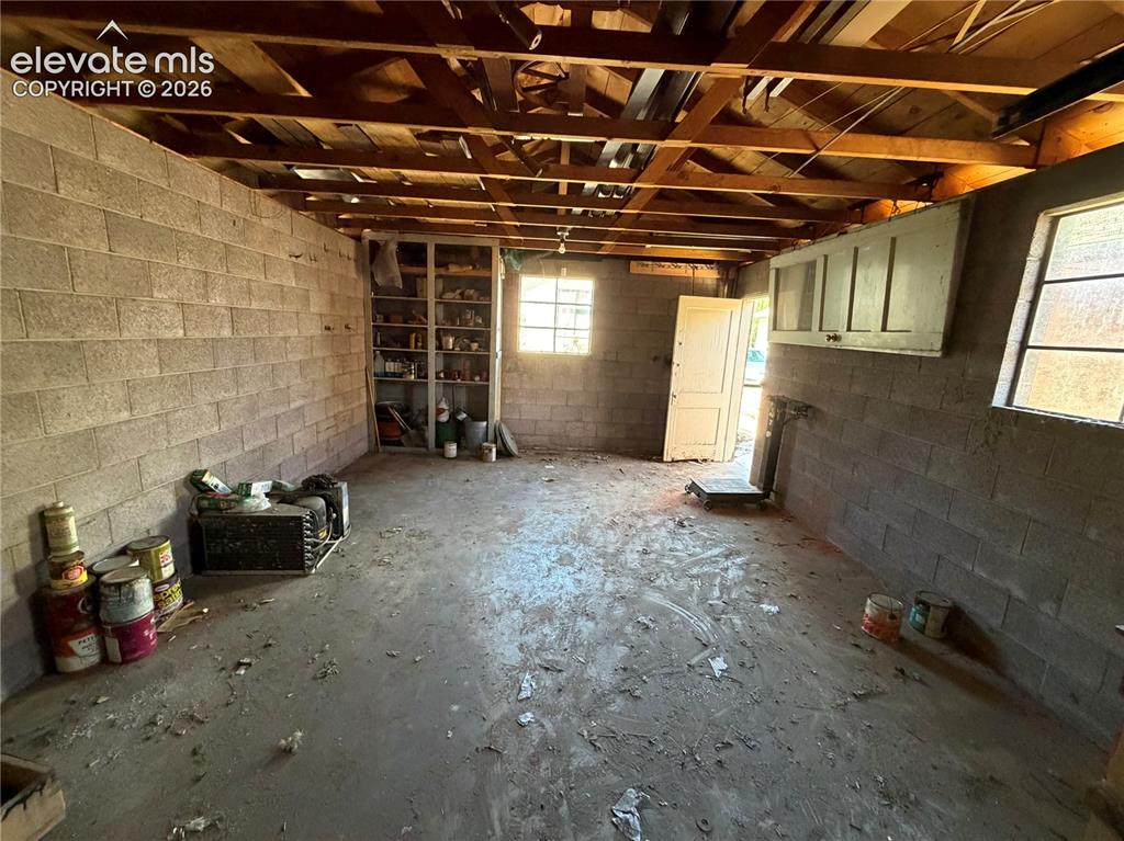 Image 23 of 28: Concrete block construction with exposed wood beam ceiling, concrete floori