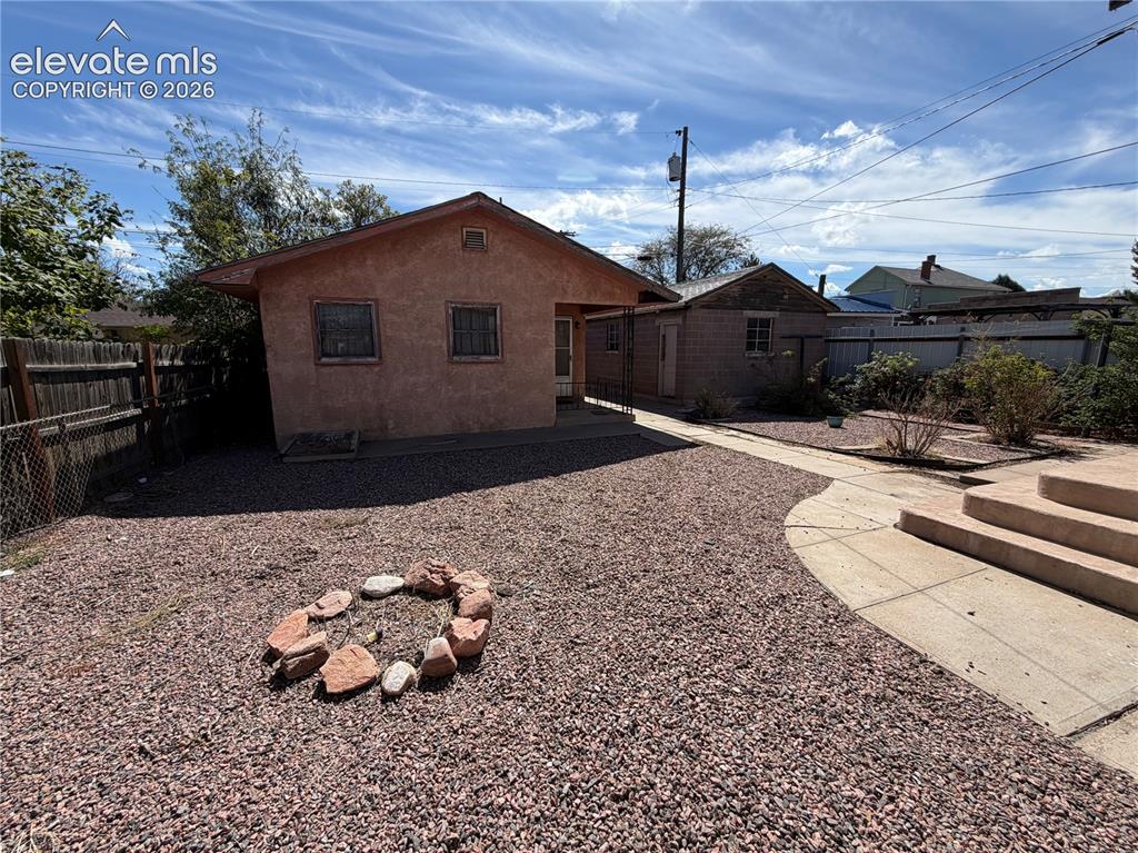 Image 28 of 28: Gravel landscaping with a stone-ringed fire pit and concrete pathways