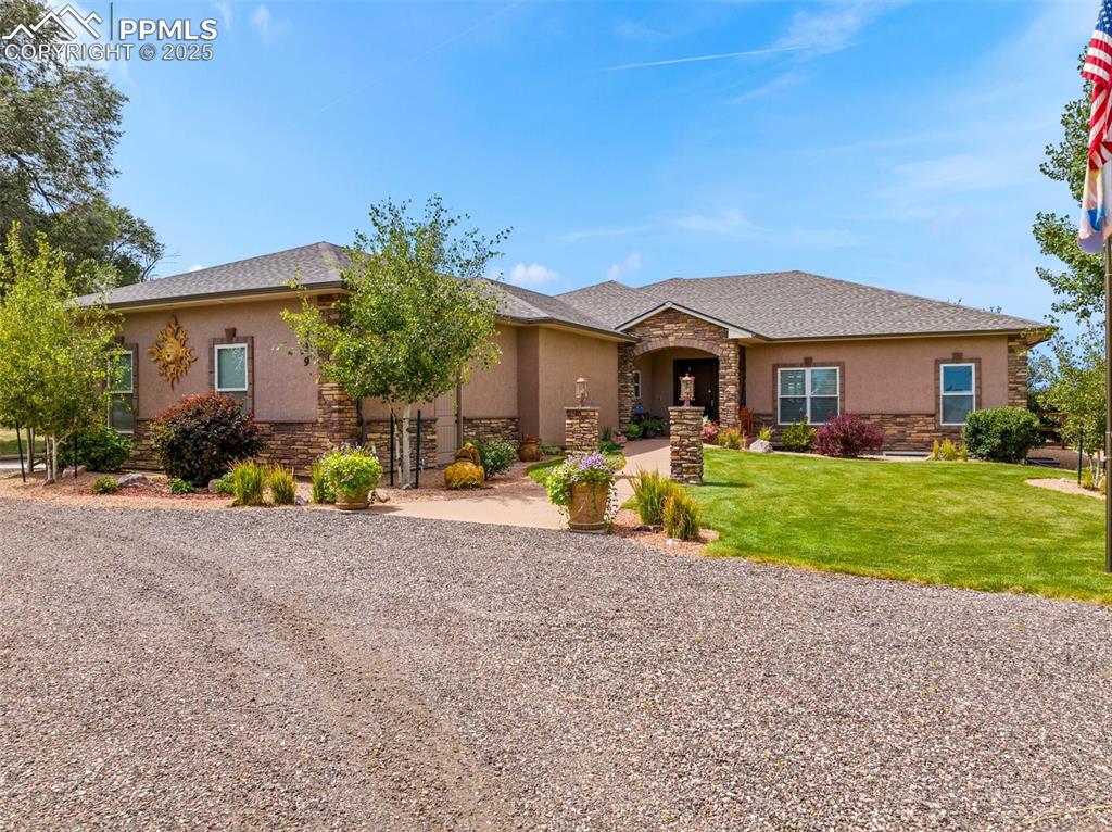 Caption: View of front of house featuring stucco siding, stone siding, and a front lawn