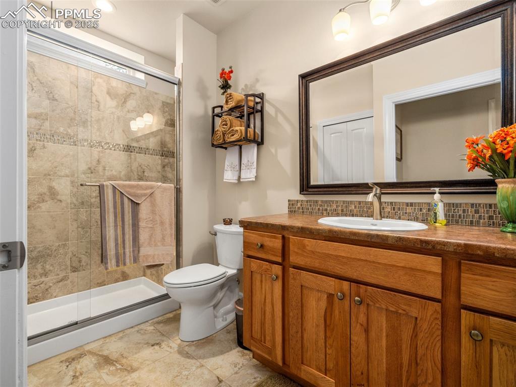 Image 35 of 46: Bathroom with decorative backsplash, vanity, toilet, and a shower stall