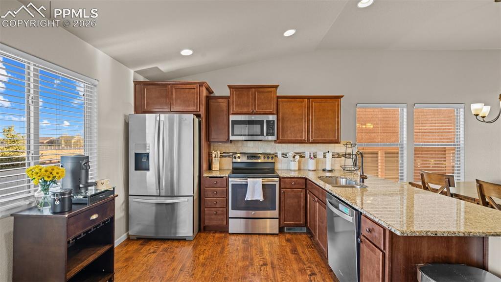 Image 12 of 27: Kitchen featuring wood-finish flooring, dark wood cabinetry, stainless stee